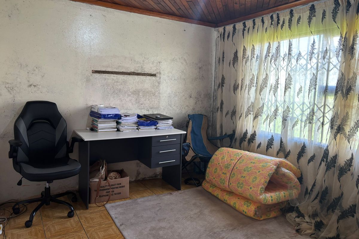 A bedroom featuring a timber ceiling and tiled flooring, currently showing significant wall surface deterioration and staining requiring maintenance and cosmetic repair.