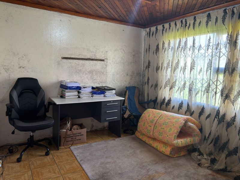 A bedroom featuring a timber ceiling and tiled flooring, currently showing significant wall surface deterioration and staining requiring maintenance and cosmetic repair.
