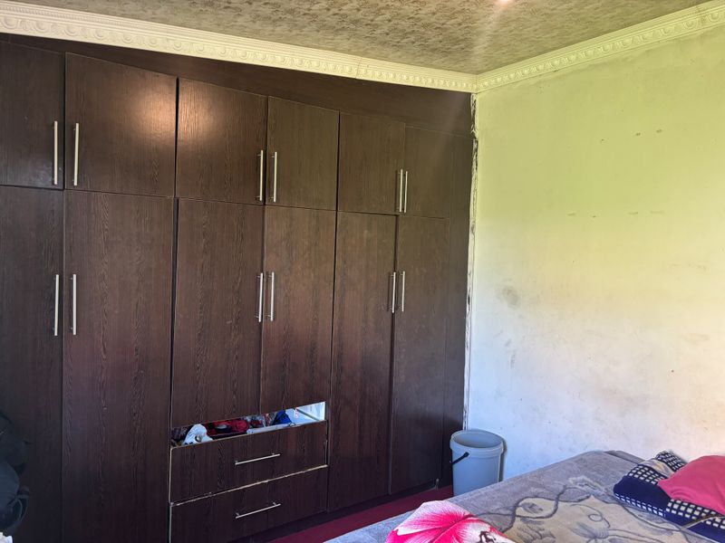 Bedroom featuring extensive dark wood built-in cupboards with modern handles, decorative ceiling cornice, and textured ceiling finish.