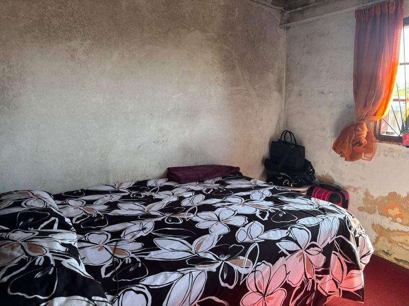 A bedroom featuring unfinished wall surfaces with visible signs of wear and paint deterioration, requiring significant cosmetic renovation.