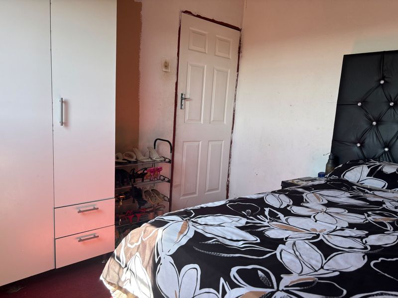A bedroom featuring a built-in wardrobe and a standard door, currently showing signs of wear and unfinished paintwork.