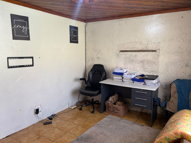 A small office space featuring timber ceiling panels and tiled flooring, currently requiring significant wall repairs and cosmetic refurbishment.