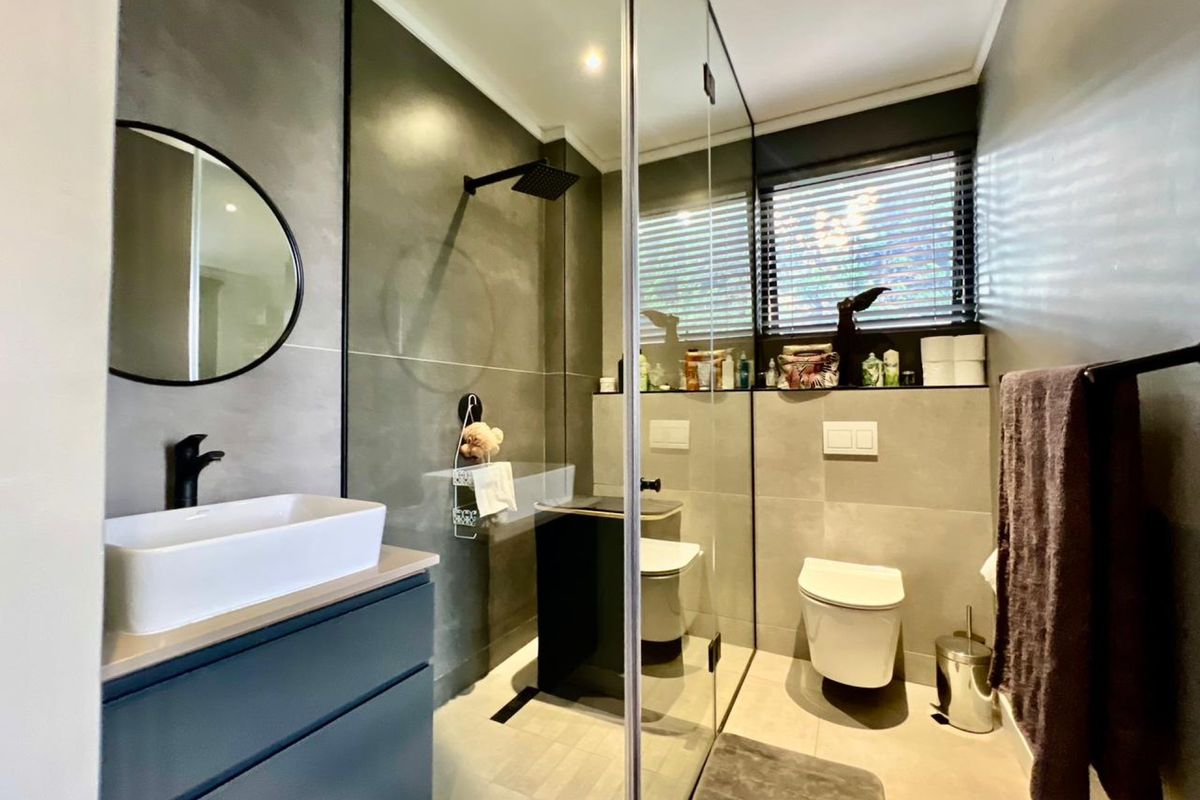 Modern bathroom featuring a glass-enclosed walk-in shower, wall-mounted toilet, and a contemporary vanity with a vessel sink and matte black fixtures.