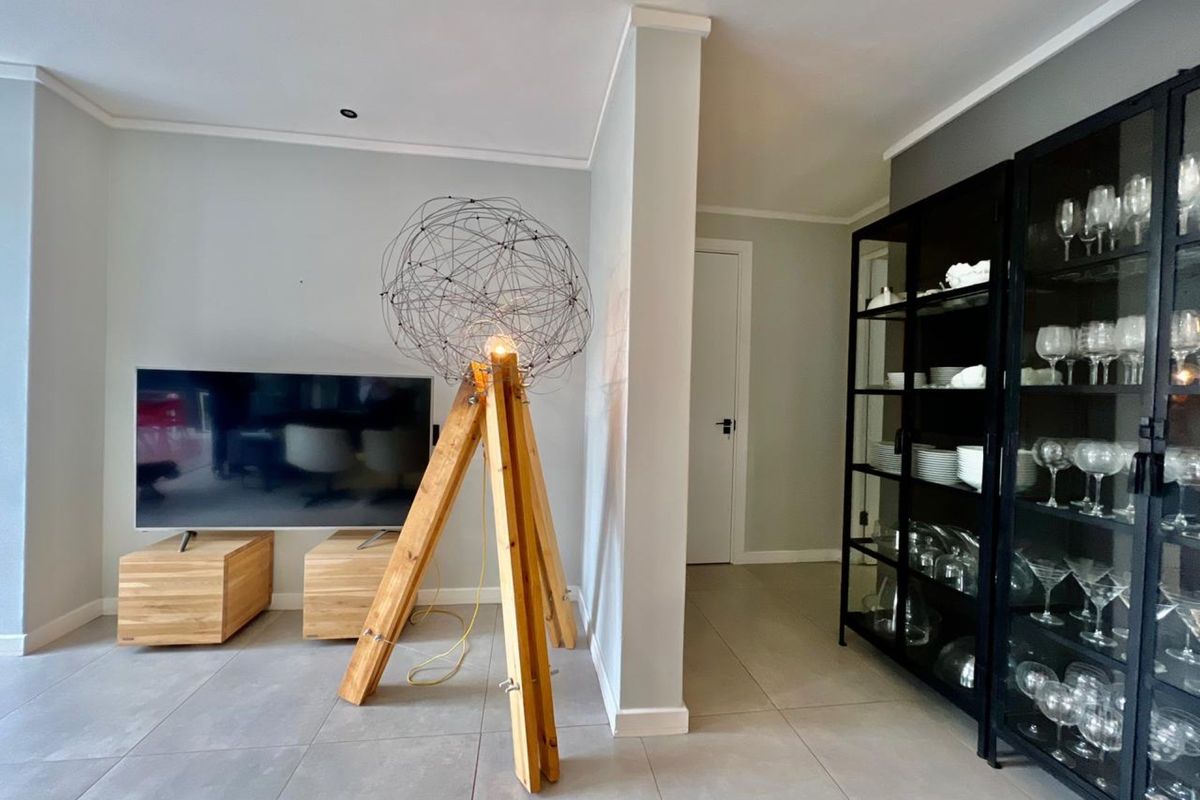 A modern living area featuring neutral tiled flooring, recessed ceiling lighting, and a clean, minimalist aesthetic with a partition wall.