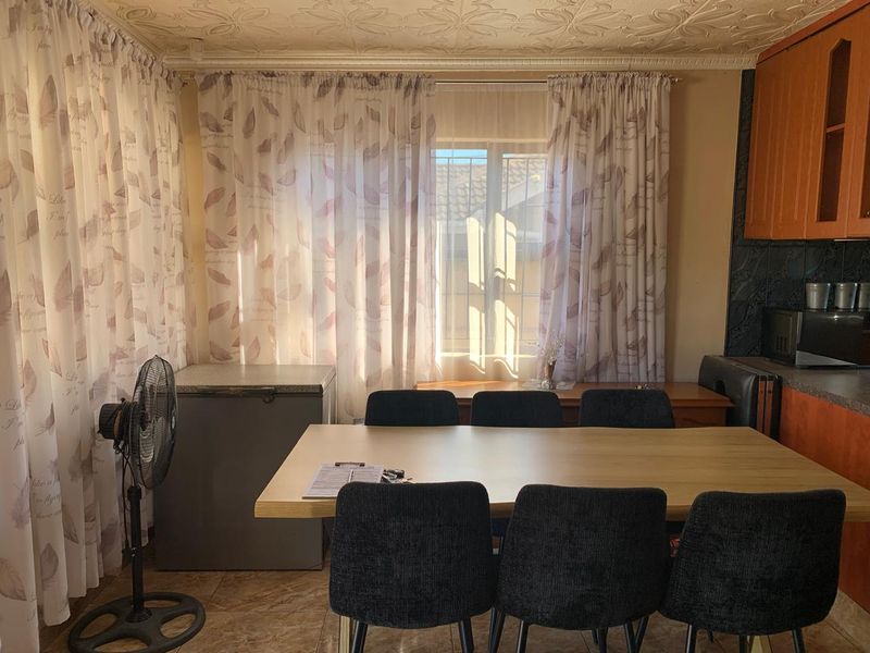 Open plan dining and kitchen area featuring tiled flooring, decorative ceiling detail, and built-in wooden cabinetry.