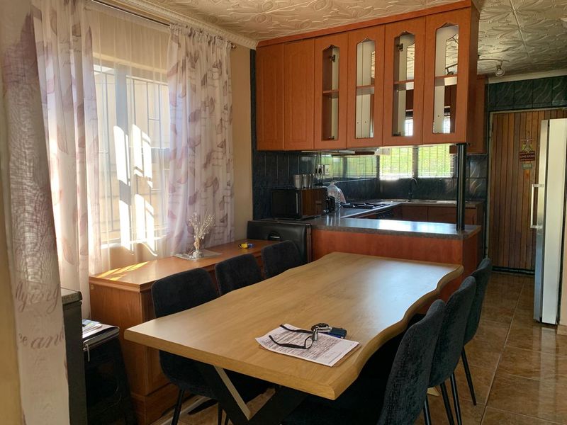 Open plan kitchen and dining area featuring wood-look cabinetry, tiled flooring, and a functional layout suitable for family meals.