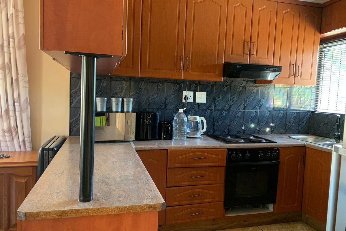 A functional kitchen featuring wood-tone cabinetry, laminate countertops, a built-in oven with hob, and a tiled backsplash.