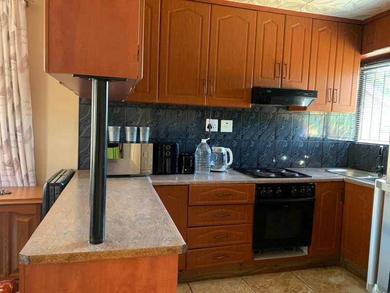 A functional kitchen featuring wood-tone cabinetry, laminate countertops, a built-in oven with hob, and a tiled backsplash.