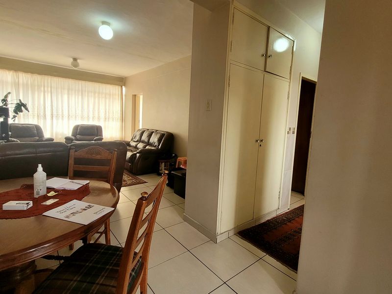 Open plan living and dining area featuring tiled flooring and built-in storage cupboards, offering a functional layout with natural light.