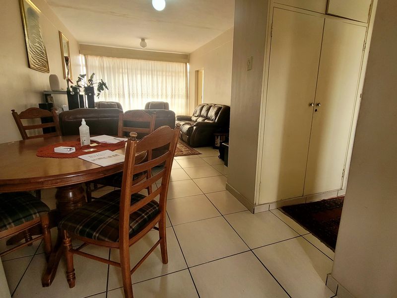 Open-plan living and dining area featuring tiled flooring and built-in storage cupboards, providing a functional and connected living space.