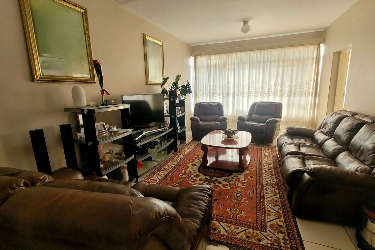 A comfortable living room featuring tiled flooring and large windows with curtain tracks, providing a functional and well-lit space.
