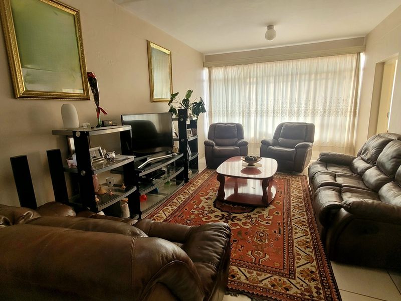 A comfortable living room featuring tiled flooring and large windows with curtain tracks, providing a functional and well-lit space.