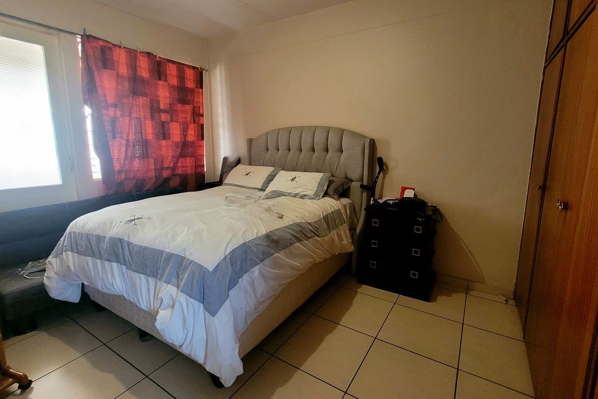 A functional bedroom featuring tiled flooring and built-in wooden cupboards, providing practical storage space.