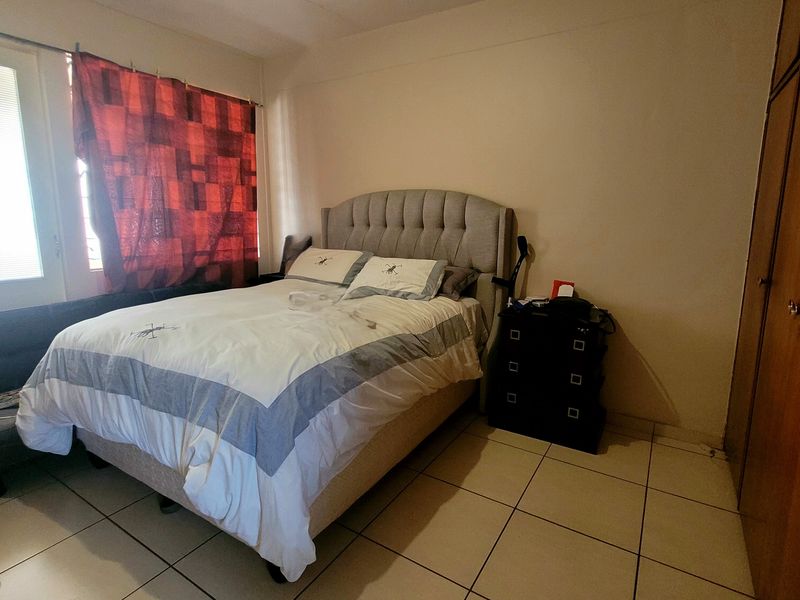 A functional bedroom featuring tiled flooring and built-in wooden cupboards, providing practical storage space.