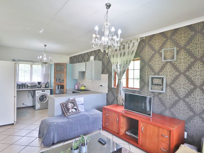 Open-plan living and kitchen area featuring tiled floors, patterned wallpaper, and a central breakfast counter, offering a functional layout for daily living.