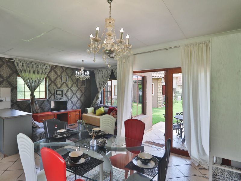 Open-plan living and dining area featuring tiled floors, a kitchen workspace, and direct access to the outdoor patio through sliding glass doors.