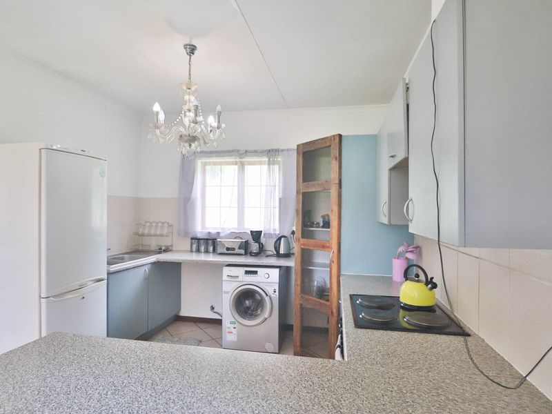 Functional kitchen featuring built-in cabinetry, laminate countertops, an electric hob, and tiled backsplash, offering a practical layout for daily meal preparation.