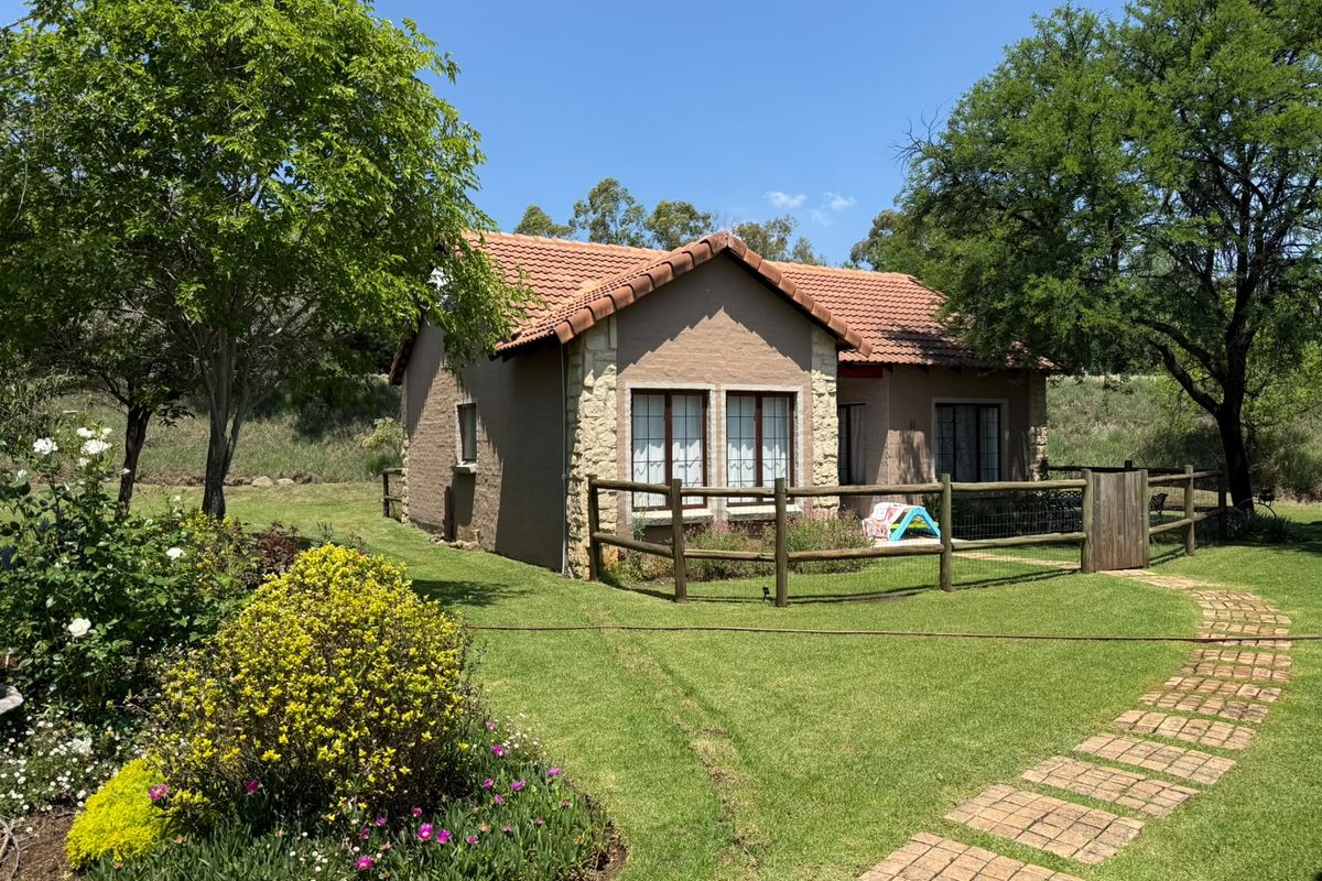 A well-maintained townhouse exterior featuring stone cladding, a tiled roof, and a landscaped garden with a brick pathway and timber fencing.