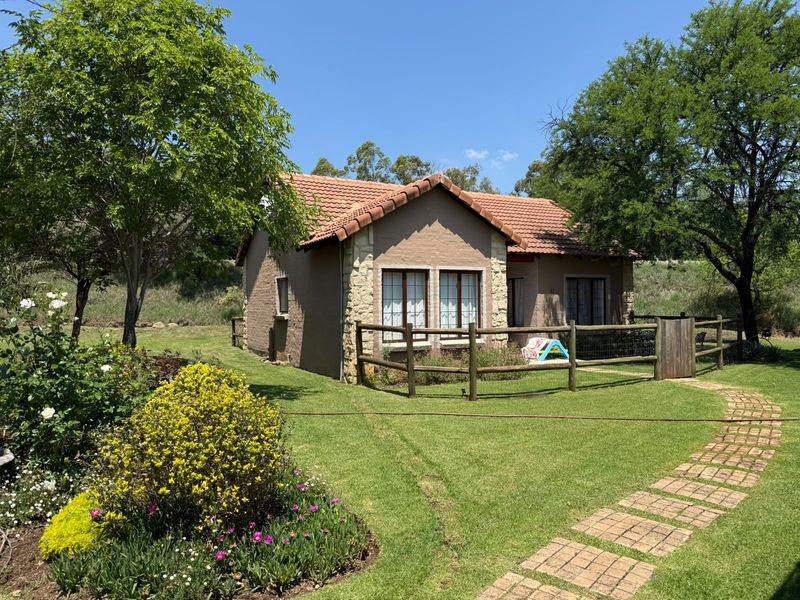 A well-maintained townhouse exterior featuring stone cladding, a tiled roof, and a landscaped garden with a brick pathway and timber fencing.