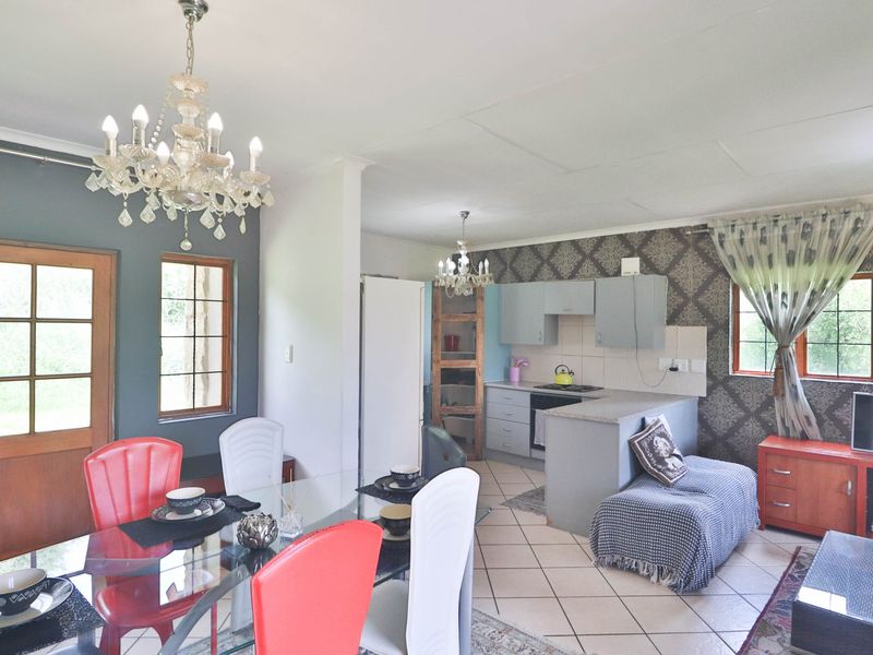 Open-plan living and kitchen area featuring tiled flooring, built-in cabinetry, and decorative wallpaper, offering a functional layout for dining and relaxation.