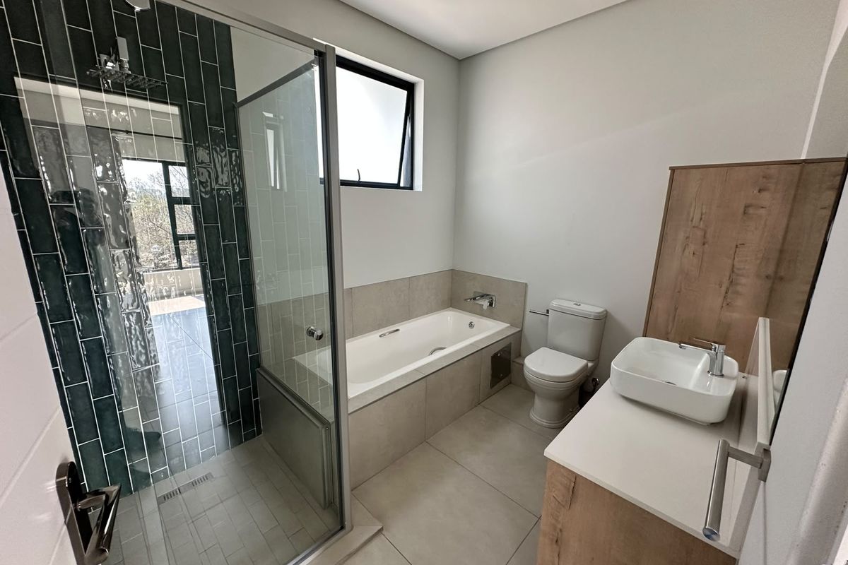 Modern bathroom featuring a glass-enclosed shower, built-in bathtub, vessel sink vanity, and contemporary tile finishes in a clean, well-maintained space.