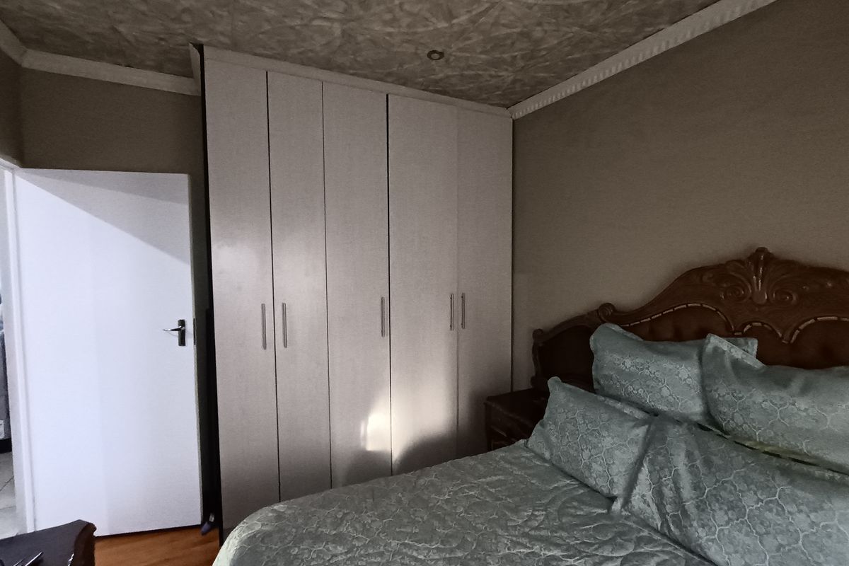 A bedroom featuring built-in cupboards, laminate flooring, and a textured ceiling finish.