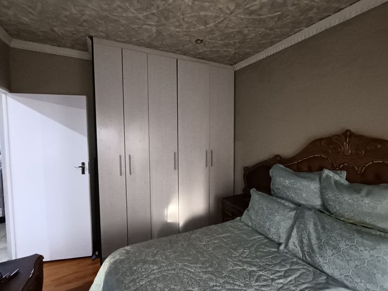 A bedroom featuring built-in cupboards, laminate flooring, and a textured ceiling finish.