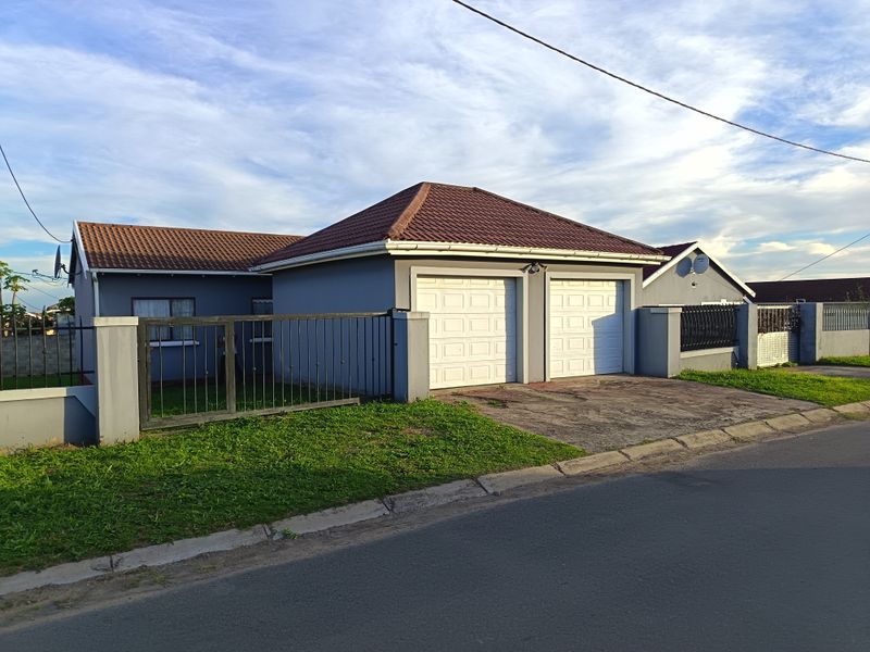 Front view of a residential property featuring a double garage, tiled roof, and secure perimeter fencing with a sliding gate.