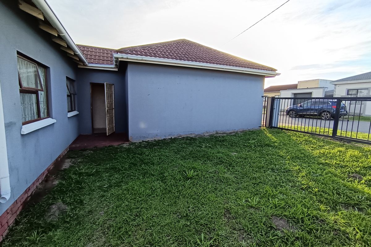 Rear view of the property featuring a tiled roof, security gate, and a small private garden area enclosed by a metal fence.