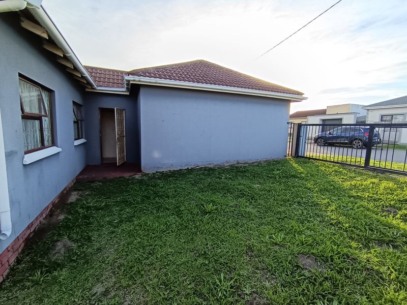Rear view of the property featuring a tiled roof, security gate, and a small private garden area enclosed by a metal fence.
