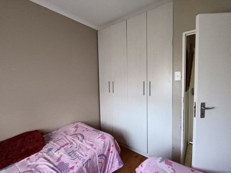 A bedroom featuring built-in cupboards and laminate flooring, providing functional storage and a neutral base for interior design.
