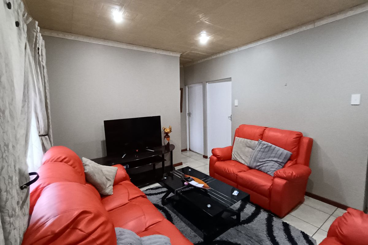 A living room featuring tiled flooring, recessed ceiling lighting, and textured ceiling tiles, providing a functional space for relaxation.