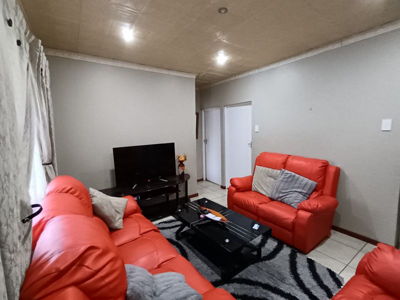 A living room featuring tiled flooring, recessed ceiling lighting, and textured ceiling tiles, providing a functional space for relaxation.