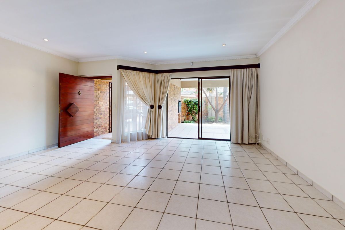 Spacious, light-filled living area featuring neutral tiled flooring, recessed lighting, and direct access to an outdoor patio through large sliding glass doors.