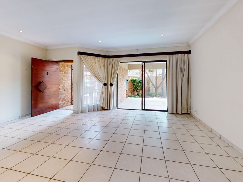 Spacious, light-filled living area featuring neutral tiled flooring, recessed lighting, and direct access to an outdoor patio through large sliding glass doors.