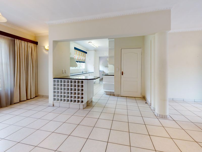 Spacious open-plan living area featuring tiled flooring, a built-in wine rack, and a functional kitchen layout with ample cabinetry.