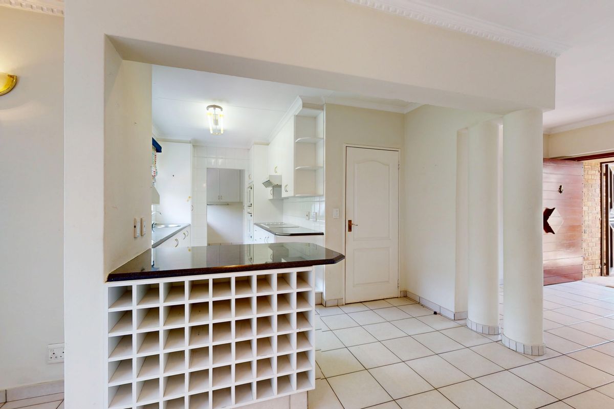 A functional kitchen featuring built-in cabinetry, a granite-topped breakfast bar with integrated wine storage, and ceramic tile flooring throughout.