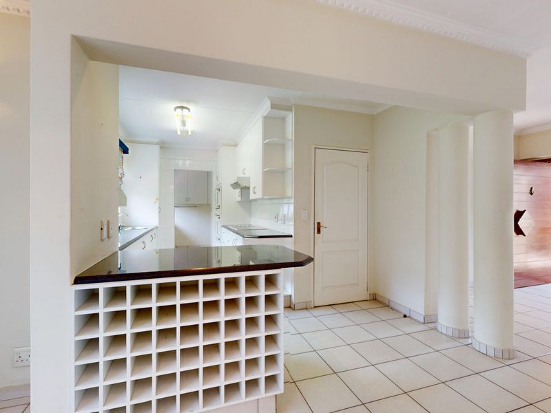 A functional kitchen featuring built-in cabinetry, a granite-topped breakfast bar with integrated wine storage, and ceramic tile flooring throughout.