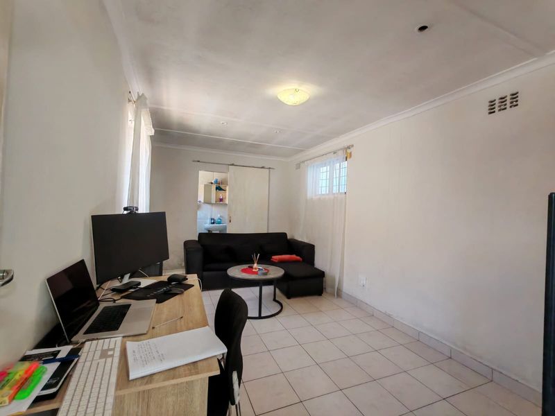 A functional living area featuring tiled flooring, a sliding door, and security bars on the window, offering a blank canvas for potential interior updates.