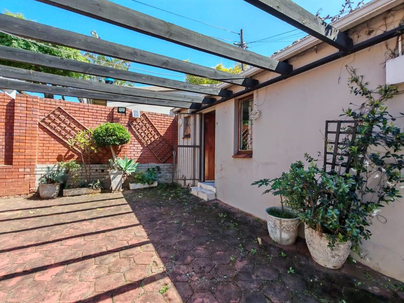 A private outdoor patio area featuring a timber pergola, brick boundary wall, and paved flooring, offering a functional space for outdoor relaxation.