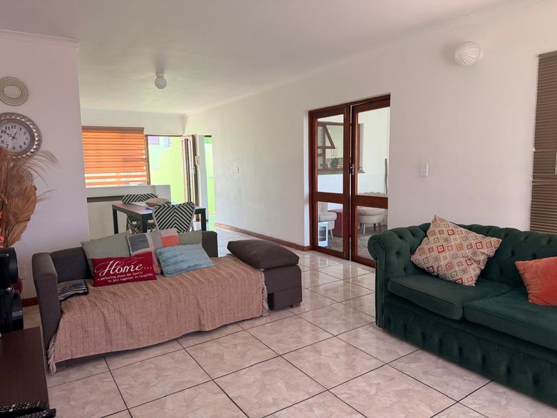 Spacious open-plan living area featuring tiled flooring, neutral walls, and double glass panel doors leading to an adjacent space.