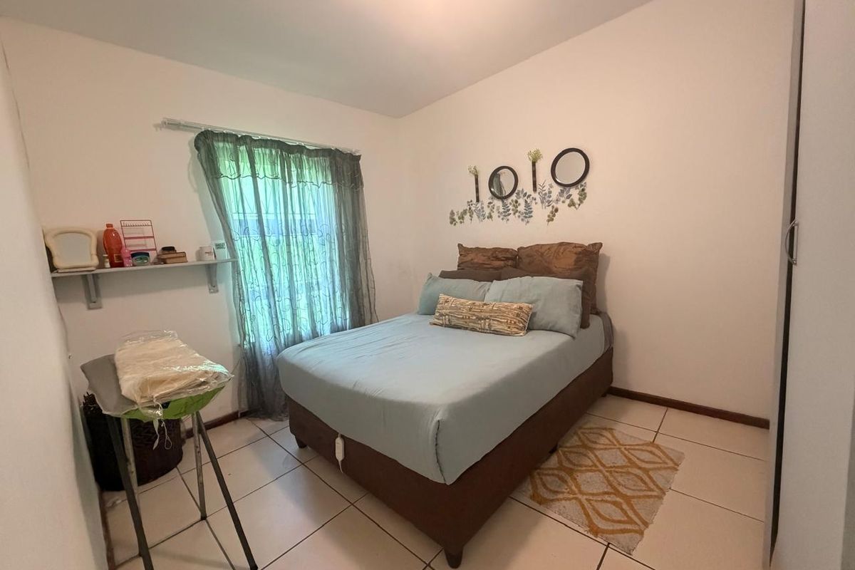 A functional bedroom featuring tiled flooring and a built-in wardrobe, offering a clean and simple living space.