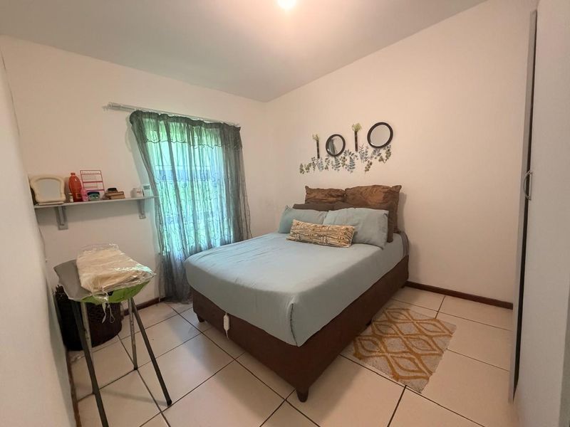 A functional bedroom featuring tiled flooring and a built-in wardrobe, offering a clean and simple living space.