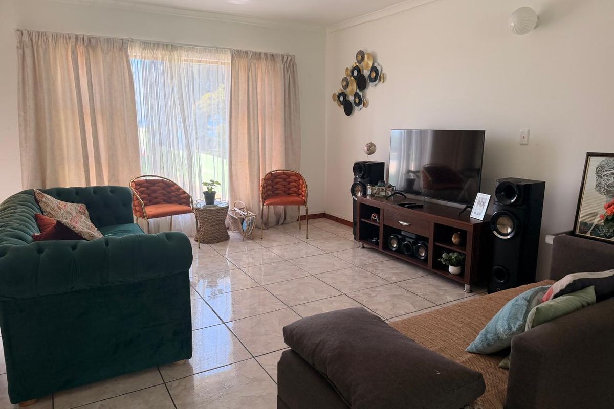 A bright living room featuring large sliding glass doors that provide natural light and access to the exterior, complemented by neutral tiled flooring.