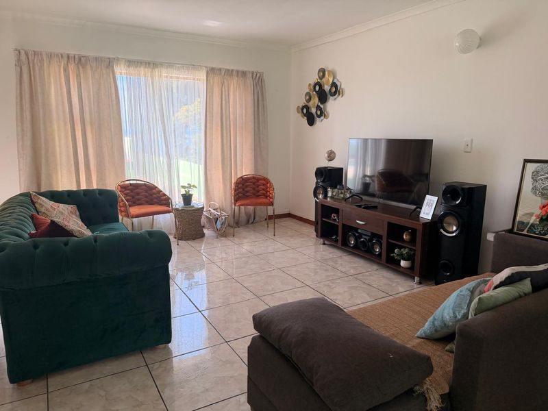 A bright living room featuring large sliding glass doors that provide natural light and access to the exterior, complemented by neutral tiled flooring.