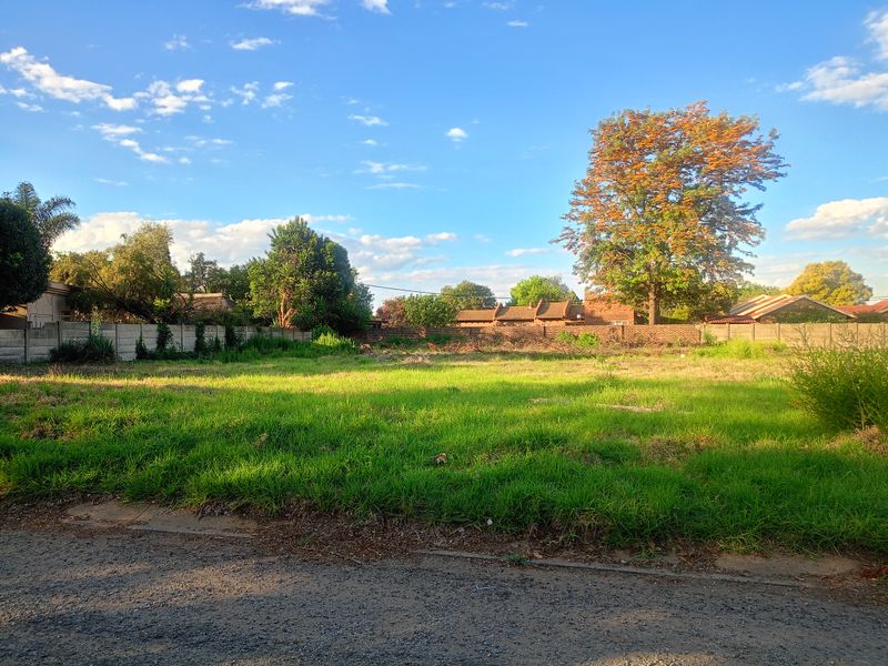 A vacant residential plot featuring a grassed surface and enclosed by a precast concrete boundary wall.