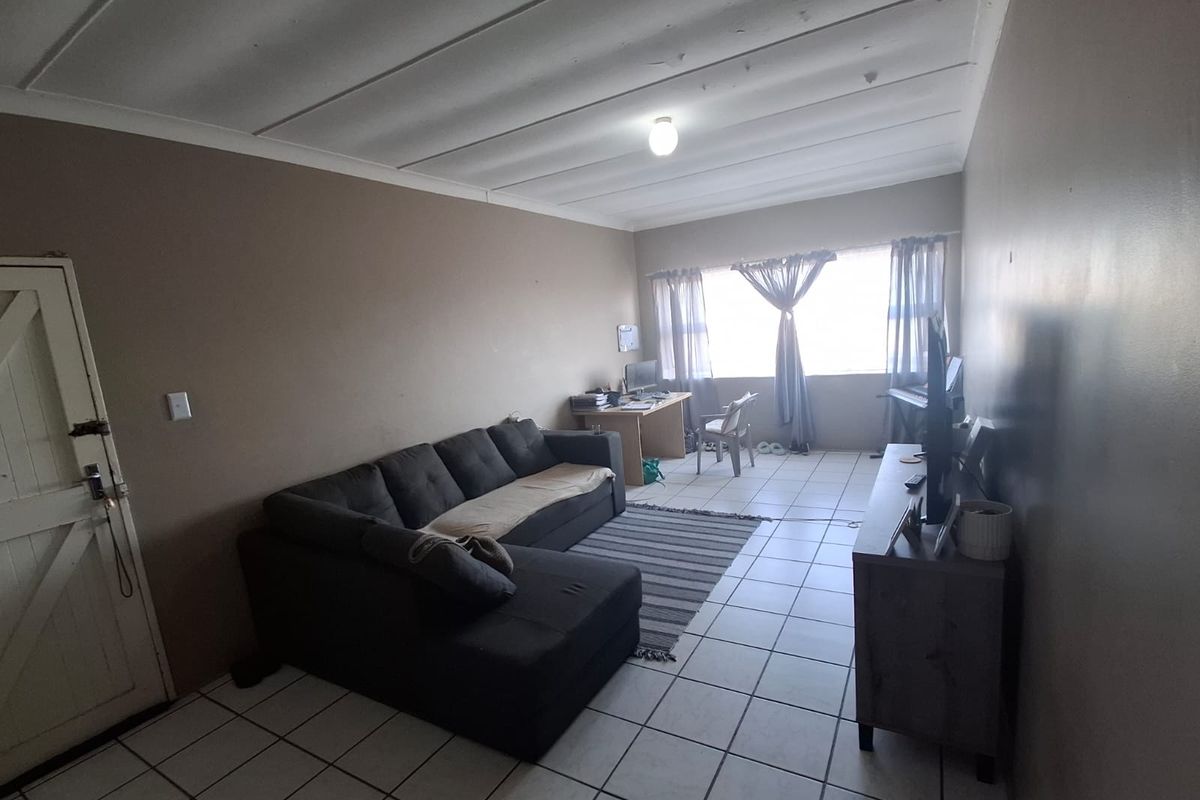 A living room featuring tiled flooring and a coved ceiling, offering a functional space with potential for cosmetic updates to enhance its appeal.