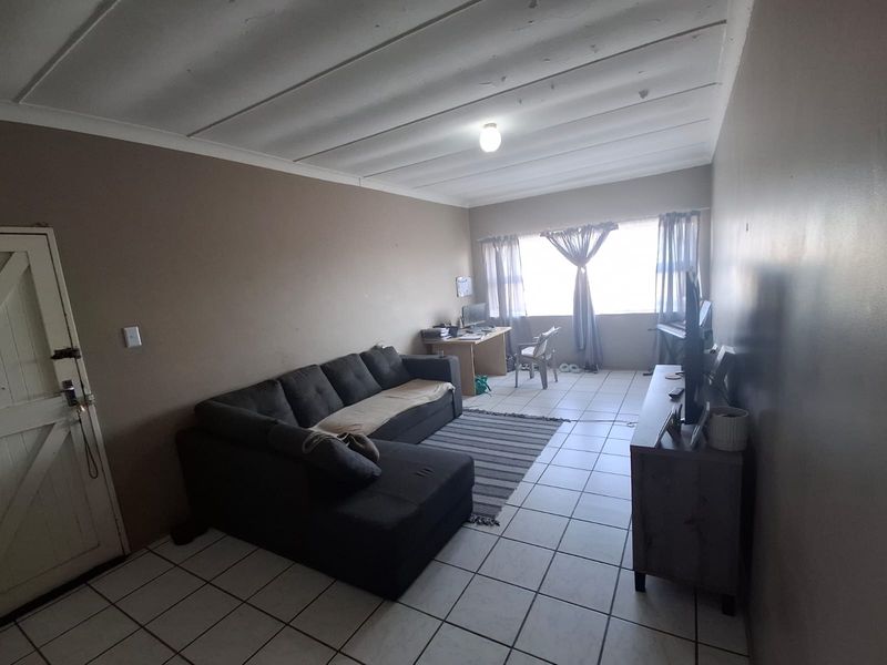 A living room featuring tiled flooring and a coved ceiling, offering a functional space with potential for cosmetic updates to enhance its appeal.