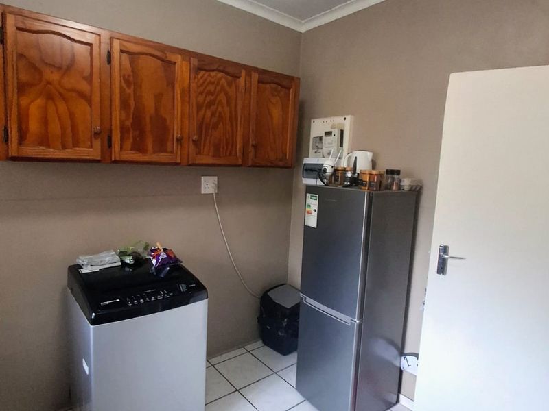 A functional laundry area featuring tiled flooring and wall-mounted wooden cabinetry, providing practical storage space for utility needs.