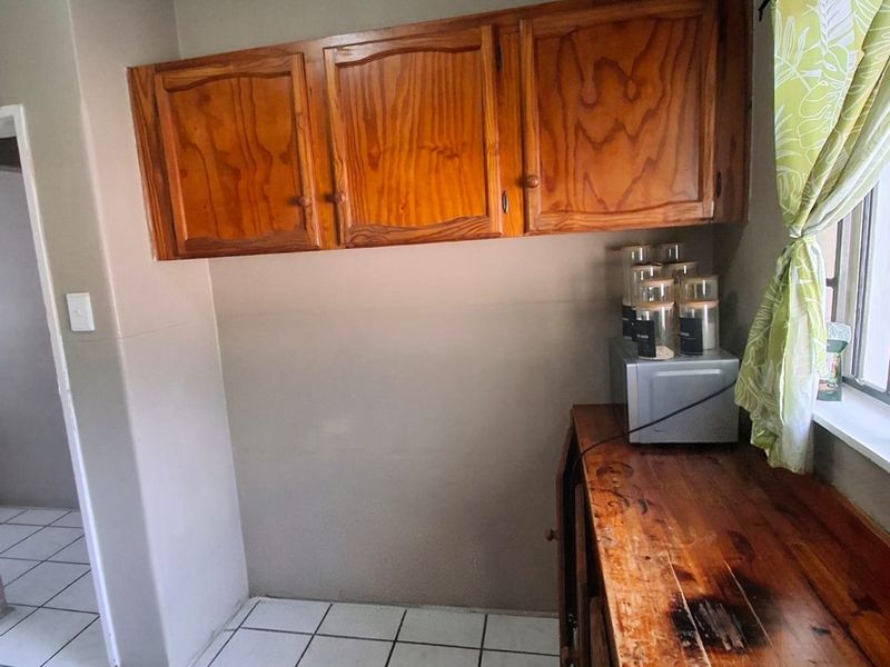 A kitchen area featuring wooden cabinetry and a worn wooden countertop with tiled flooring, offering potential for a modern renovation.